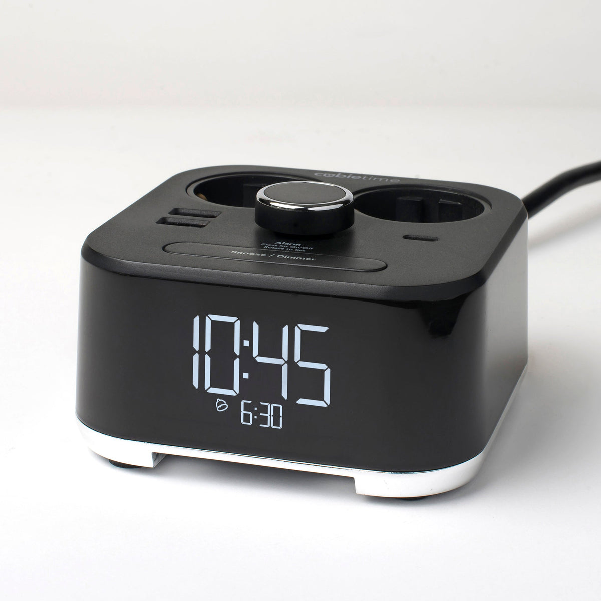 A black digital alarm clock with dual charging ports and a power cord, shown on a clean white background.